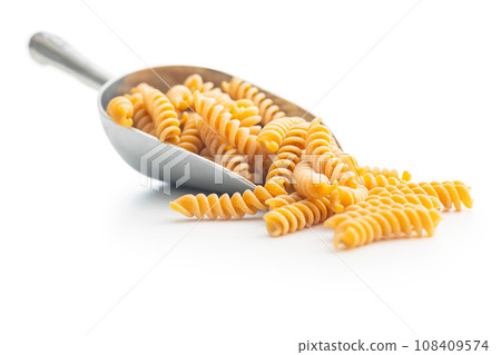 Raw whole grain fusilli pasta. Uncooked pasta in scoop isolated on white background. 108409574