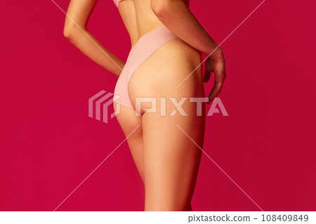 Back view of cropped perfect body shape female body, buttocks, legs in against red studio background. Concept of dieting. Back view of cropped perfect body shape female body, buttocks, legs in against red studio background. Concept of dieting. 108409849