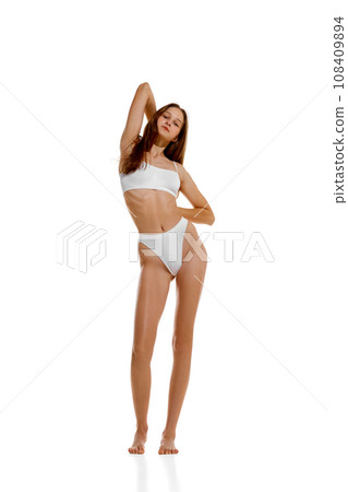 Young beautiful fit woman with long hair posing in white lingerie showing her ideal athlete forms isolated studio background. Young beautiful fit woman with long hair posing in white lingerie showing her ideal athlete forms isolated studio background. 108409894