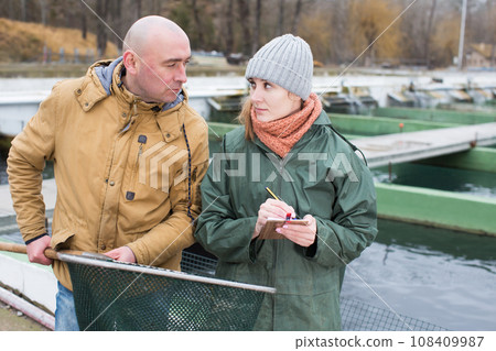 Woman noting tasks of male fish farmer 108409987
