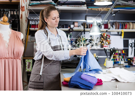 Female professional sewer with textile at sewing workshop 108410073