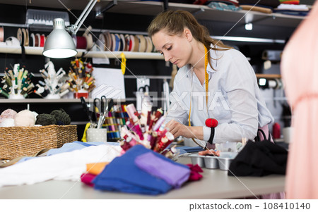 Woman sew up textile material at workplace at sewing workshop 108410140