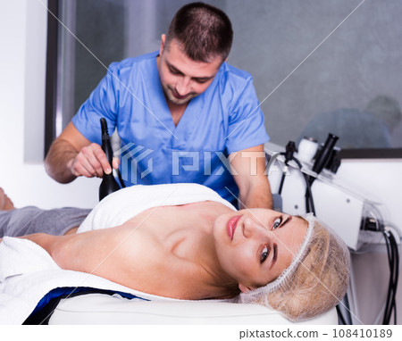 Woman receiving hardware body treatment 108410189