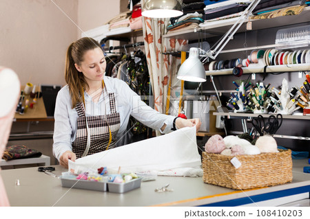 Female seamstress is cutting textile for create new dress Female seamstress is cutting textile for create new dress 108410203