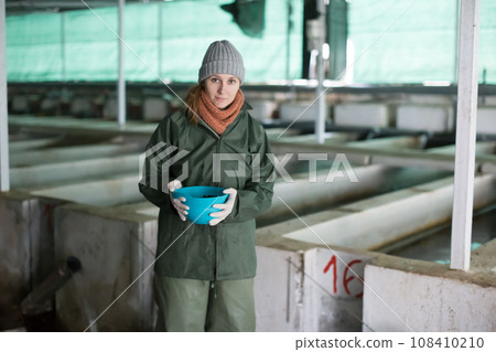 Female feeding fish on sturgeon farm Female feeding fish on sturgeon farm 108410210