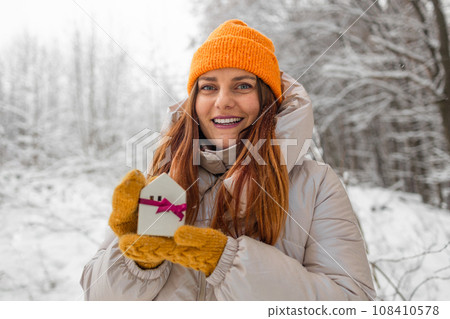 Christmas and New Year miniature house in woman hands outdoors. Copy space for text. Winter card. Holiday and celebration concept.  108410578