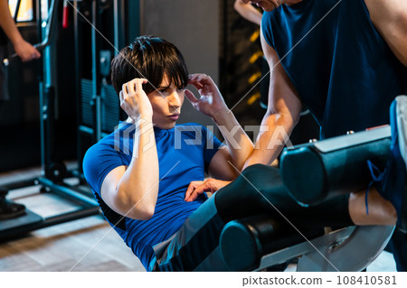 A man receiving guidance from a trainer at a fitness gym 108410581