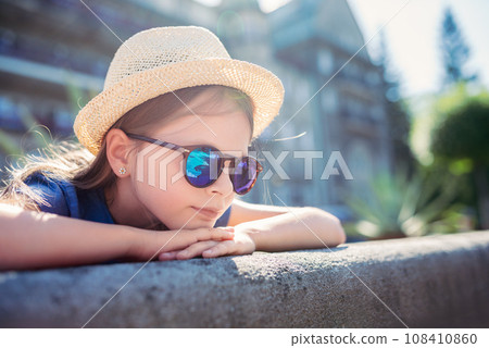 Portrait of a beautiful little girl in a hat and sunglasses. 108410860