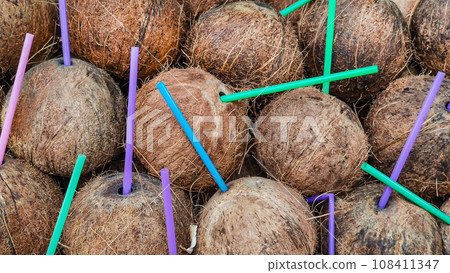 Coconut background with colorful cocktail drinking tubes 108411347