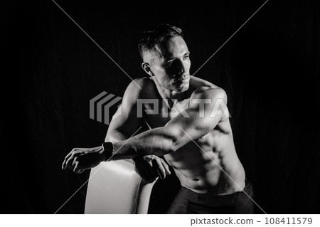 Confident, attractive shirtless muscular young man topless in studio Confident, attractive shirtless muscular young man topless in studio 108411579
