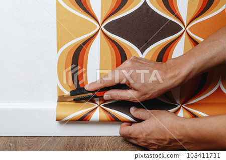 man cutting the edges of the wallpaper 108411731