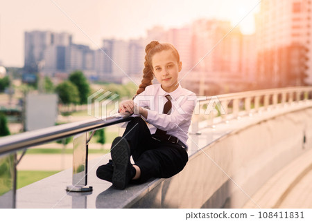 Young schoolgirl in a white classical blouse posing in the city Young schoolgirl in a white classical blouse posing in the city 108411831
