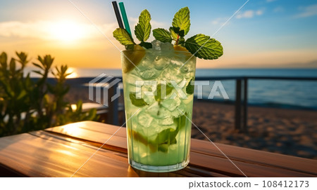 Mojito on a table in a cafe on a sandy beach in the rays of sunset, an idea for advertising or a menu in a cafe or restaurant. Free space, non-alcoholic popular cooling drinks, summer vacation time 108412173