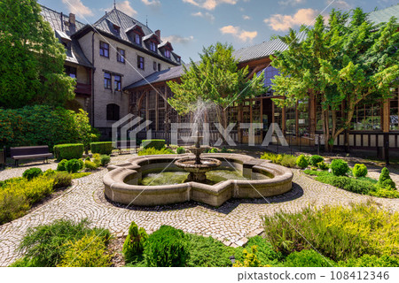 Swieradow-Zdroj, Poland - June 24, 2019; Spa House - a stone fountain in front of the side entrance to the longest Walking Hall in Lower Silesia (80 meters) 108412346