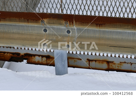 Old guardrail standing in the snow 108412568