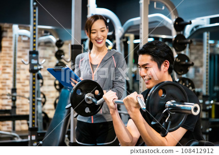 一名男子在健身房接受教練的指導 一名男子在健身房接受教練的指導 108412912