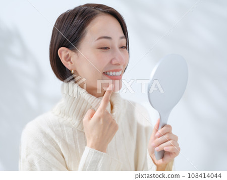 A woman checking with a hand mirror 108414044