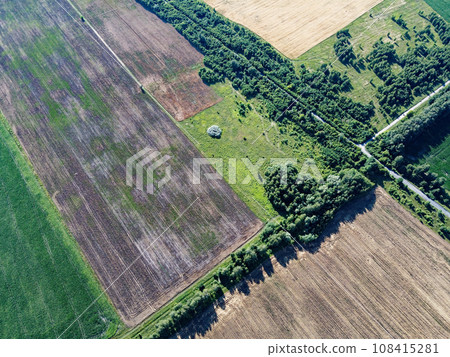 Crossroads of two roads among farm fields, aerial view. Agrarian landscape, bird's-eye view. Crossroads of two roads among farm fields, aerial view. Agrarian landscape, bird's-eye view. 108415281