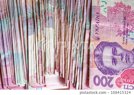 A close-up photo of a stack of Ukrainian Hryvnia banknotes, showcasing the various denominations and colors. A bunch of banknotes with a face value of two hundred hryvnias. Ukrainian money. 108415324