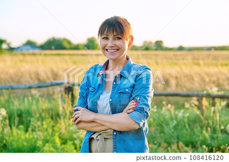 Portrait of smiling middle aged woman looking at camera, summer countryside Portrait of smiling middle aged woman looking at camera, summer countryside 108416120