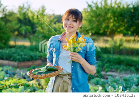 Woman with zucchini harvest, zucchini flowers, on farm Woman with zucchini harvest, zucchini flowers, on farm 108416122