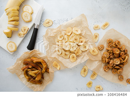 Various crunchy and chewy banana slices and chips snack with raw banana and knife.Top view. 108416484
