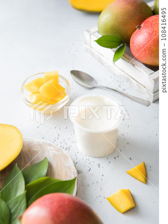 Greek style yogurt with mango and fresh fruits on light board. Greek style yogurt with mango and fresh fruits on light board. 108416495