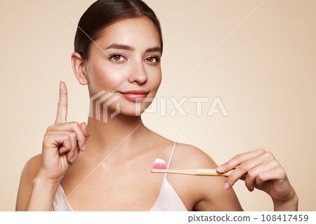 Beautiful young woman brushing her teeth 108417459