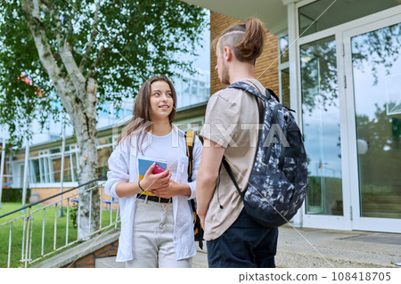 Meeting of two teenage students, guy and girl, near educational building 108418705