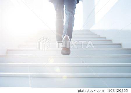 Businessman climbing the stairs towards the light Businessman climbing the stairs towards the light 108420265