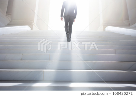 Businessman climbing the stairs towards the light Businessman climbing the stairs towards the light 108420271