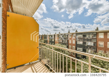 a balcony with some buildings in the background and blue sky above it, as seen from an apartment building's balcony 108420795