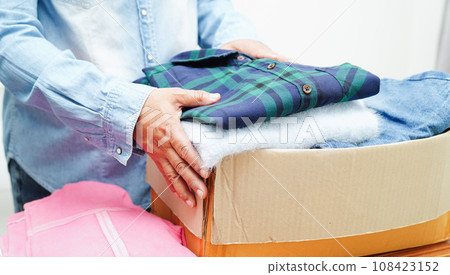 Clothes donations in cardboard box for volunteer. 108423152