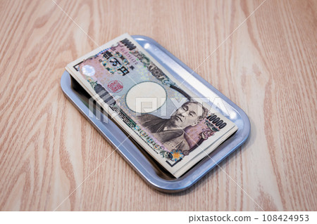 Japanese 10,000 yen bills are placed in change trays for businesses and purchases. Japanese 10,000 yen bills are placed in change trays for businesses and purchases. 108424953