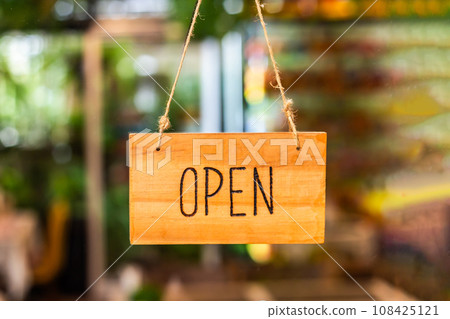 Wooden open sign in front of a cafe or shop with dissolved background 108425121