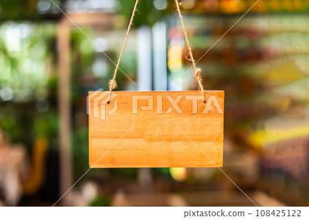 Blank wooden sign in front of a cafe or shop with dissolved background. Copy space 108425122
