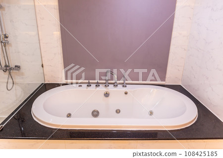 White bathtub with warm lighting against with hot and cold water faucet White bathtub with warm lighting against with hot and cold water faucet 108425185
