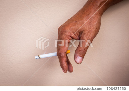 Close-up of a man's hand working hard smoking a cigarette with smoke. Background texture Close-up of a man's hand working hard smoking a cigarette with smoke. Background texture 108425260