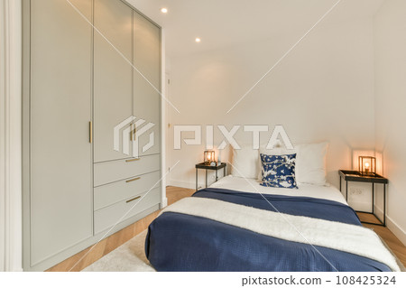 a bedroom with white walls and wood flooring the room has a bed, two nightstands and a night stand 108425324