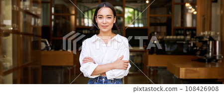 Portrait of young female entrepreneur, asian business owner or manager, sitting confident, smiling at camera with arms crossed 108426908