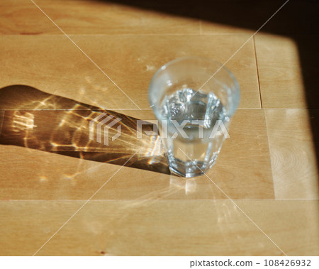 Natural light enters a glass of water, creating a beautiful pattern. 108426932