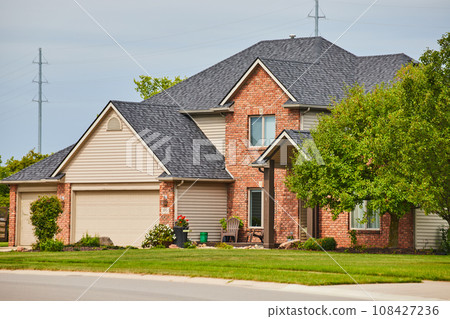 Suburban home with reddish brown brick face and overhang over front door side view Suburban home with reddish brown brick face and overhang over front door side view 108427236