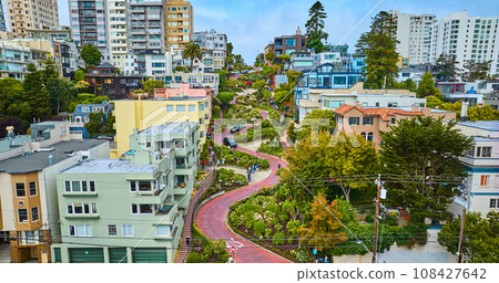 Straight on aerial of Lombard Street with cars and people winding down road lined by houses 108427642