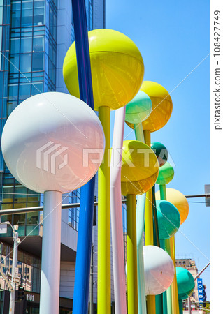 Shiny colorful balls of yellow and white with shades of blue and green on poles abstract sculpture 108427749