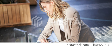 Portrait of businesswoman looks at her digital watch to check time, standing outside on street near office 108427997