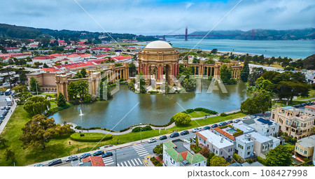 Aerial Palace of Fine Arts colonnade and open rotunda on pond with city and Golden Gate Bridge 108427998