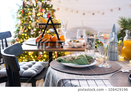 Serving a festive table with snacks, salads and goodies close-up in the modern interior of a loft house decorated for Christmas and New Year. Waiting for guests for a festive dinner 108429196