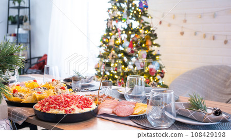 Serving a festive table with snacks, salads and goodies close-up in the modern interior of a loft house decorated for Christmas and New Year. Waiting for guests for a festive dinner 108429198