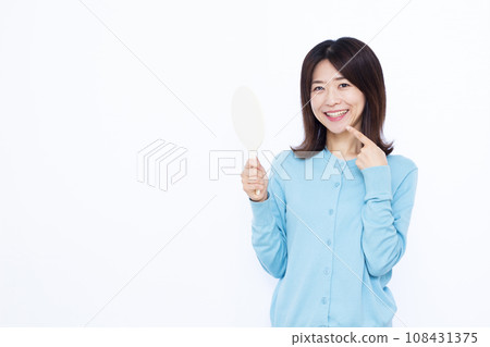 A woman in her 30s pointing at her teeth A woman in her 30s pointing at her teeth 108431375