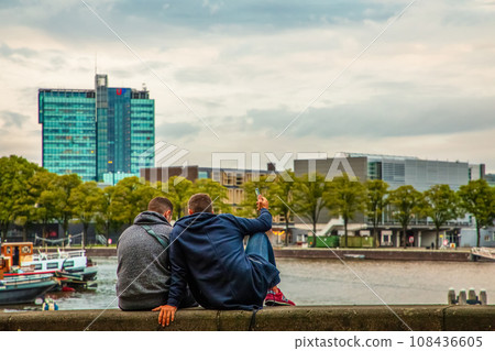 modern Amsterdam city center. two guys are sitting on bank 108436605